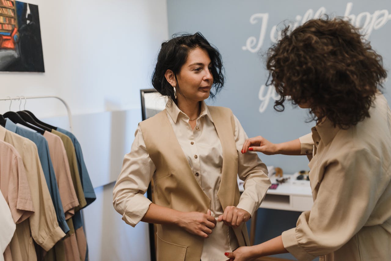 cta-bg A fashion stylist helps a woman adjust her outfit in a trendy boutique.