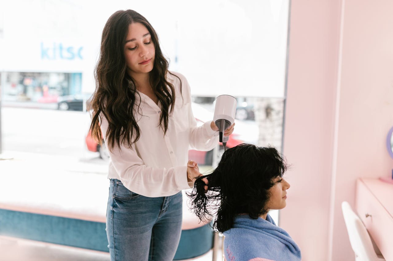 testimonials-img A hairdresser dries a clients hair in a modern salon setting, providing expert hairdressing services.